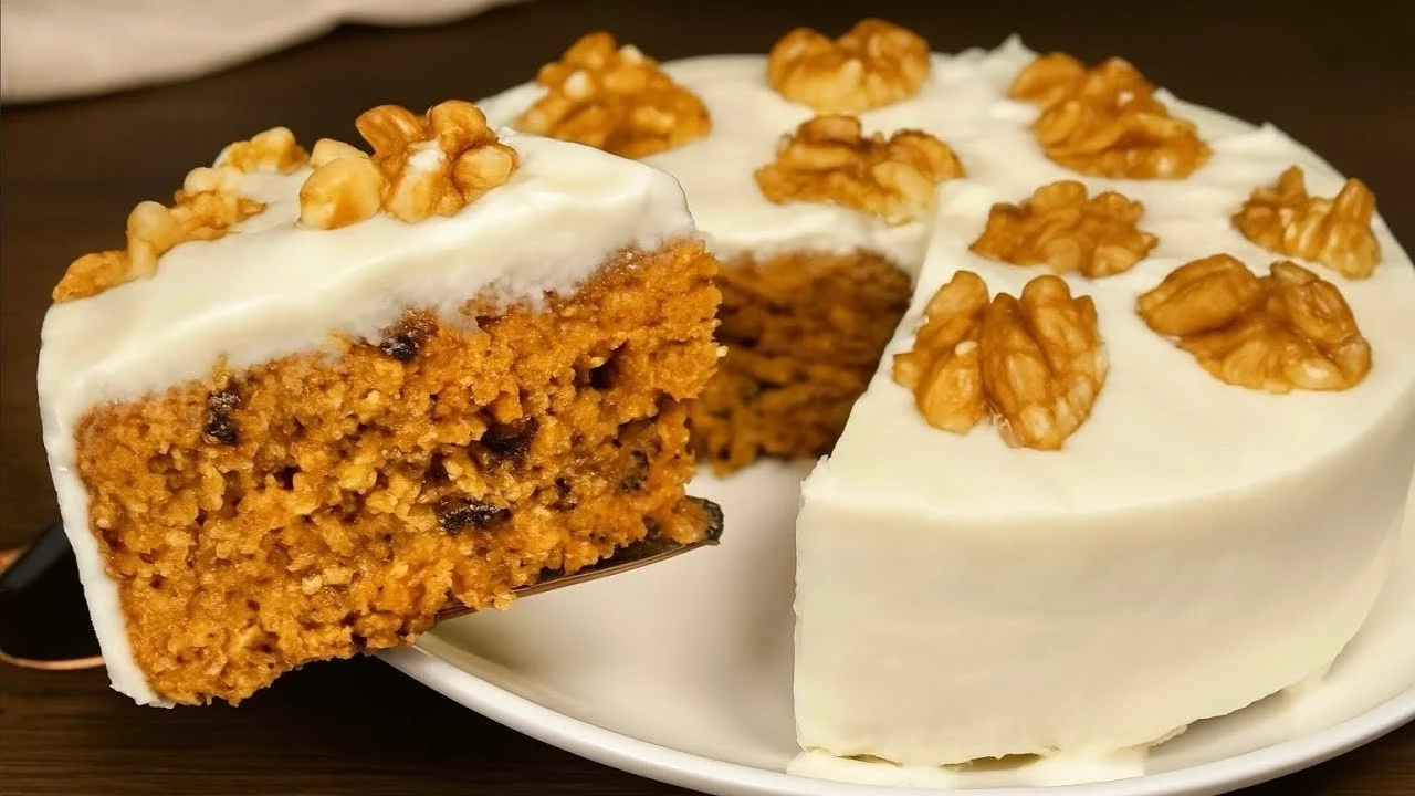 Sárgarépa zabkása torta szelet tálalva, díszítve dióval és friss zöldségekkel.